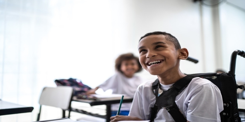 Boy in wheelchair smiling in classroom 